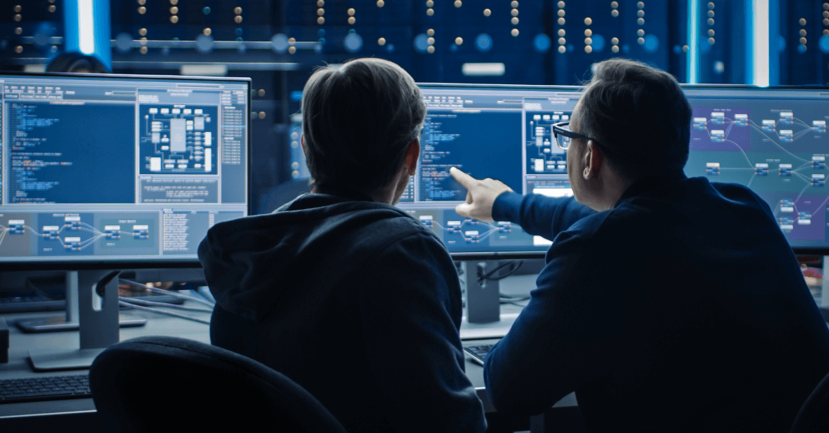 Two colleagues reviewing cybersecurity threat data on computer monitor